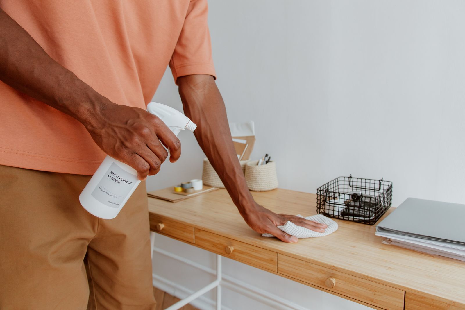 Cleaner wiping down an office desk with spray and cloth