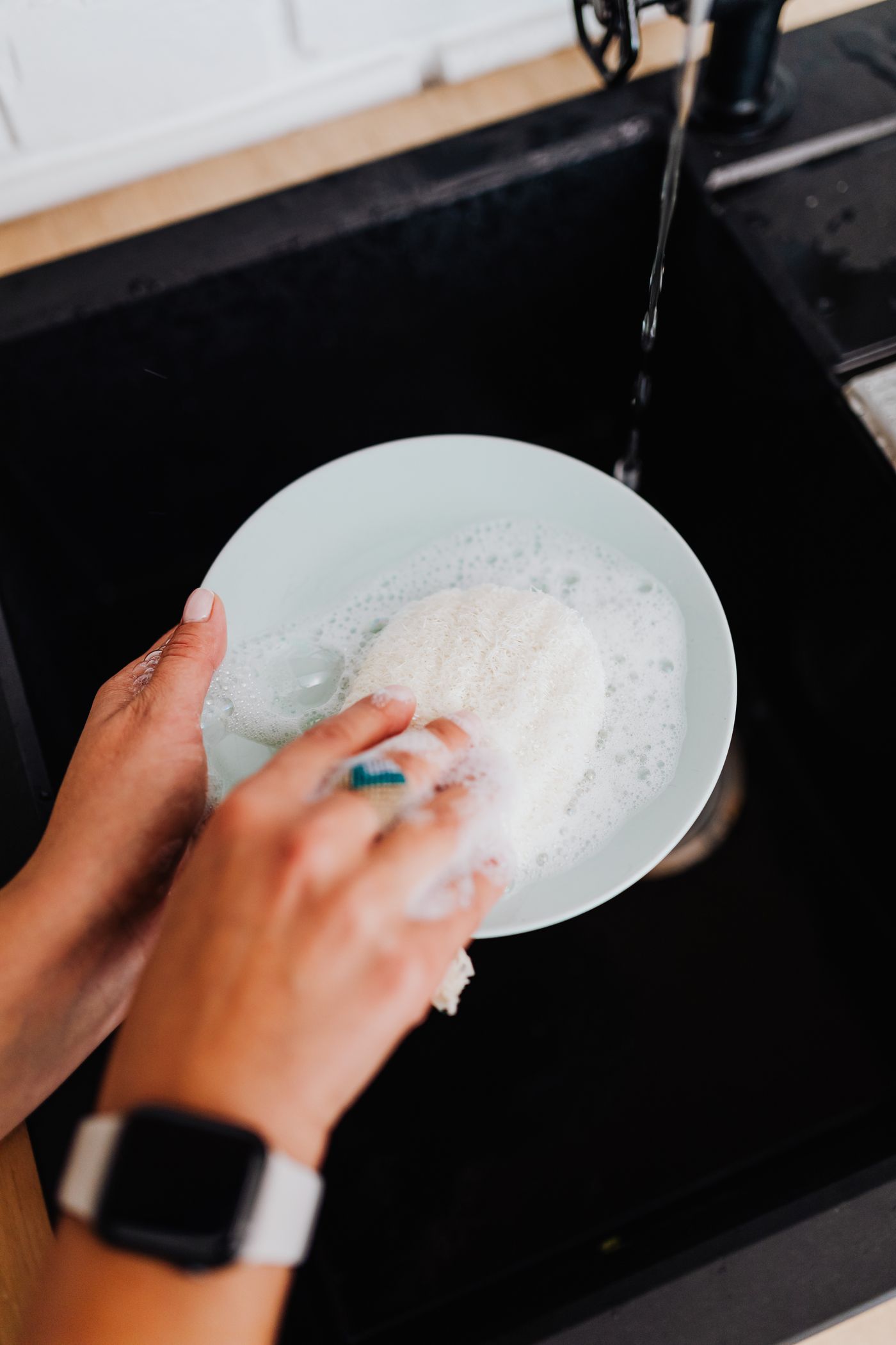Close-up of hands washing a plate at the sink